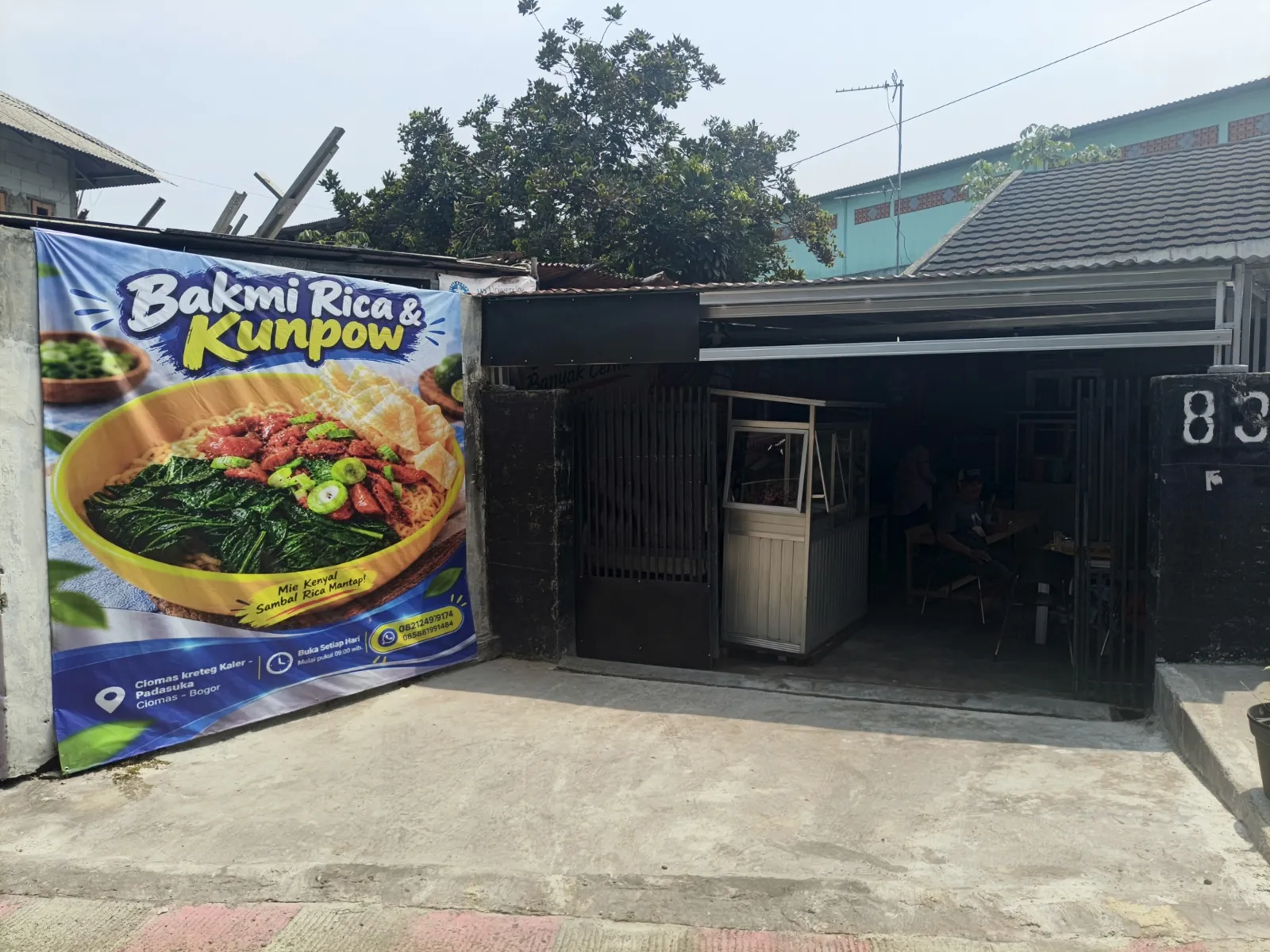 Tampak depan warung Bakmi Kunpow dengan spanduk biru di sebelah kiri